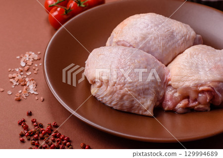 Meat, raw chicken thigh, leg in skin with salt and spices. Raw chicken thigh 129994689