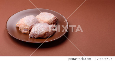 Meat, raw chicken thigh, leg in skin with salt and spices. Raw chicken thigh 129994697