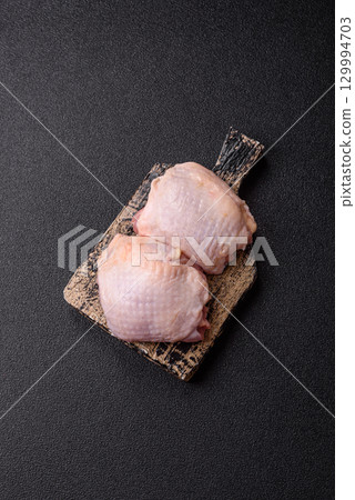 Meat, raw chicken thigh, leg in skin with salt and spices. Raw chicken thigh Meat, raw chicken thigh, leg in skin with salt and spices. Raw chicken thigh 129994703