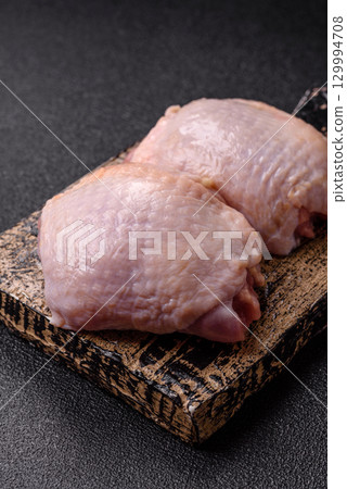 Meat, raw chicken thigh, leg in skin with salt and spices. Raw chicken thigh 129994708