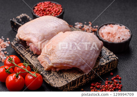 Meat, raw chicken thigh, leg in skin with salt and spices. Raw chicken thigh 129994709
