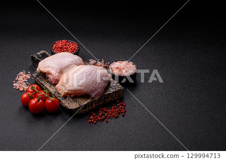 Meat, raw chicken thigh, leg in skin with salt and spices. Raw chicken thigh 129994713