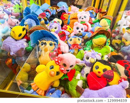 Stuffed toys inside a claw machine. Childhood, leisure, play and amusement in an arcade entertainment setting. Stuffed toys inside a claw machine. Childhood, leisure, play and amusement in an arcade entertainment setting. 129994839