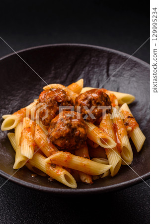 Penne pasta with meatballs in tomato sauce with salt and spices. Italian food penne pasta 129995234