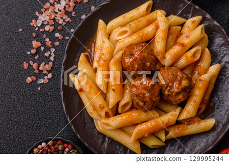 Penne pasta with meatballs in tomato sauce with salt and spices. Italian food penne pasta 129995244
