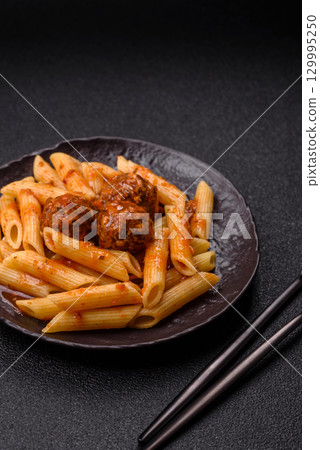 Penne pasta with meatballs in tomato sauce with salt and spices. Italian food penne pasta 129995250