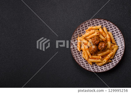 Penne pasta with meatballs in tomato sauce with salt and spices. Italian food penne pasta 129995256