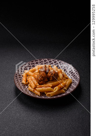 Penne pasta with meatballs in tomato sauce with salt and spices. Italian food penne pasta 129995258