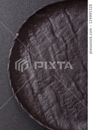 Empty round black plate for food, risotto or pasta. Empty plate on dark background Empty round black plate for food, risotto or pasta. Empty plate on dark background 129995328