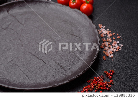 Empty round black plate for food, risotto or pasta. Empty plate on dark background 129995330