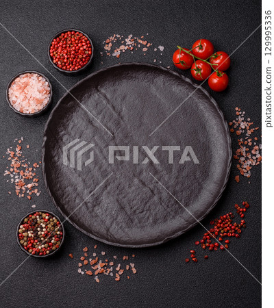Empty round black plate for food, risotto or pasta. Empty plate on dark background 129995336