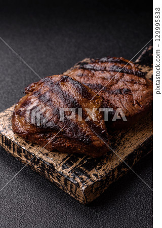 Grilled beef steak meat with salt and pepper. Beef steak grilled on a barbecue 129995838