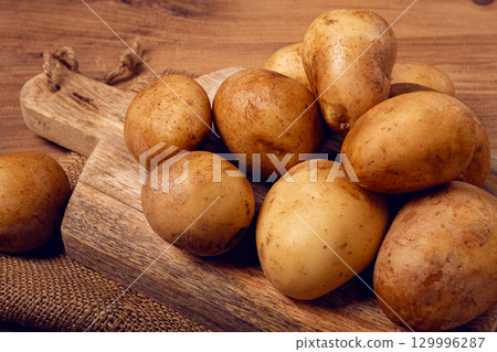 Raw potatoes, scattered on a chopping board, close-up, no people, 129996287