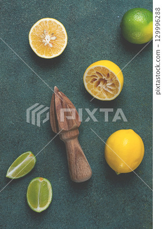Wooden citrus reamer, manual lemon juicer, made of acacia wood, with citrus fruits on the table, top view, 129996288