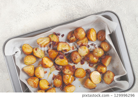 Crispy roasted potatoes with herbs and bacon on a baking tray ready to serve for a delicious meal 129996296