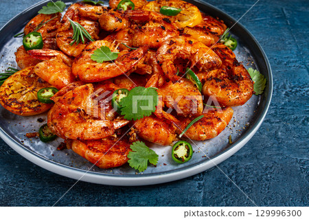grilled shrimp, unpeeled, headless, with spices, on a dark blue table, homemade, no people, 129996300
