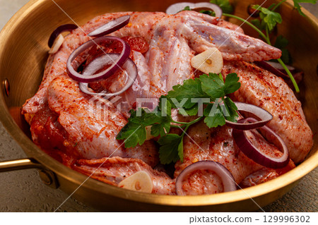 Chicken wings, in a brass saucepan, ready for cooking, grilling or baking, in a home kitchen, no people Chicken wings, in a brass saucepan, ready for cooking, grilling or baking, in a home kitchen, no people 129996302
