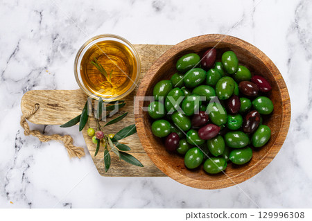 Chalkidiki olives, classic Greek green olives, in a bowl on a cutting board, top view, without people, Chalkidiki olives, classic Greek green olives, in a bowl on a cutting board, top view, without people, 129996308