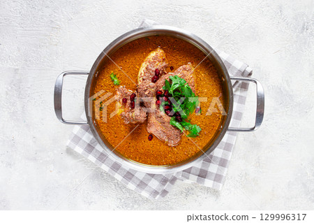 fesenjan, an Iranian dish, stewed chicken, in a nut-pomegranate sauce, in a saucepan,light background, homemade, no people, 129996317