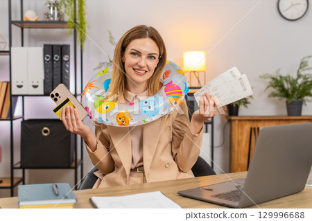 Businesswoman buys vacation tickets with credit card and smartphone smiles ends work wears swim ring Businesswoman buys vacation tickets with credit card and smartphone smiles ends work wears swim ring 129996688
