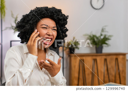 African American businesswoman argues loudly on smartphone upset by dispute during tense phone call 129996740