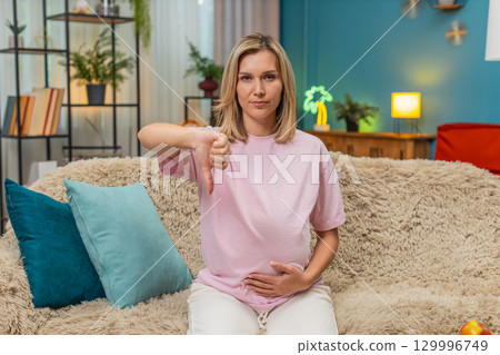Pregnant woman giving thumbs down dislike gesture showing negative review unhappy rejection feedback Pregnant woman giving thumbs down dislike gesture showing negative review unhappy rejection feedback 129996749