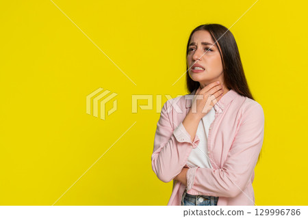 Woman pressing hands to throat squinting in pain showing discomfort while swallowing sore throat 129996786