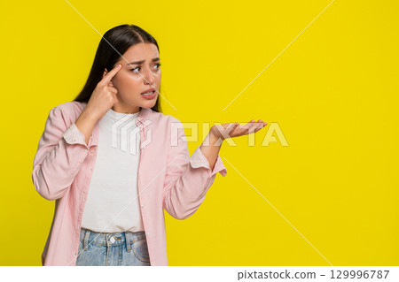 Woman tapping finger on temple with sarcastic expression showing disbelief silly irrational decision 129996787