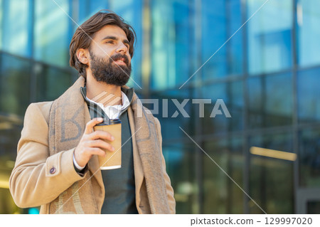 Happy Indian business man tourist enjoying morning coffee hot drink walking on city downtown street 129997020