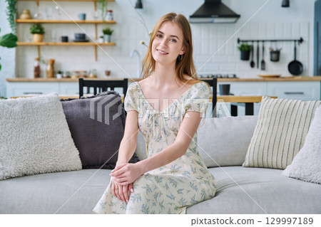 Portrait beautiful smiling young woman at home looking at camera sitting on sofa Portrait beautiful smiling young woman at home looking at camera sitting on sofa 129997189