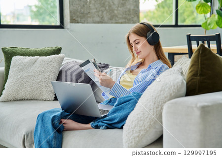 Young teen girl student in headphones with laptop textbook watching video lesson at home Young teen girl student in headphones with laptop textbook watching video lesson at home 129997195