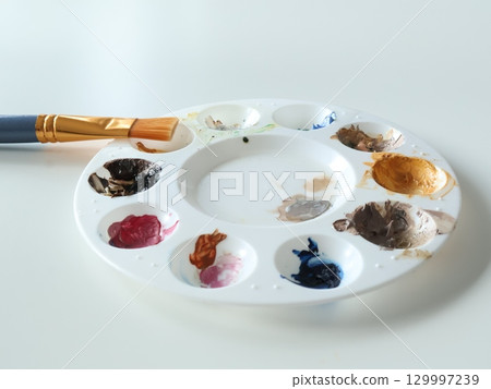 Artist Palette and Brush With Vibrant Colors on a Studio Desk 129997239