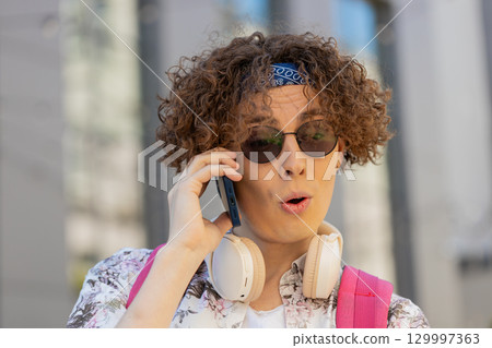 Happy young man tourist having remote conversation communicate speaking by smartphone with friends Happy young man tourist having remote conversation communicate speaking by smartphone with friends 129997363