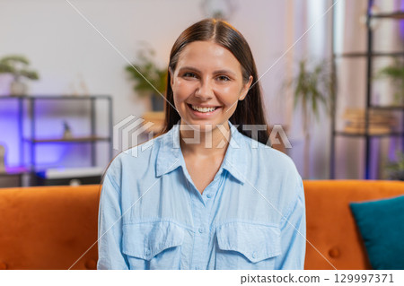 Portrait of happy calm Caucasian woman at home couch smiling friendly, looking at camera resting Portrait of happy calm Caucasian woman at home couch smiling friendly, looking at camera resting 129997371