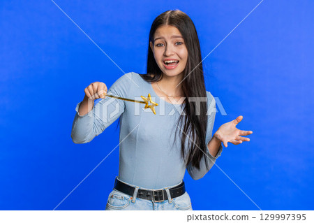 Magician witch young woman gesturing with magic wand making wish come true, casting magician spell 129997395