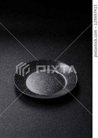 Empty round black plate for food, kitchen utensils on dining table. Empty plate Empty round black plate for food, kitchen utensils on dining table. Empty plate 129997415
