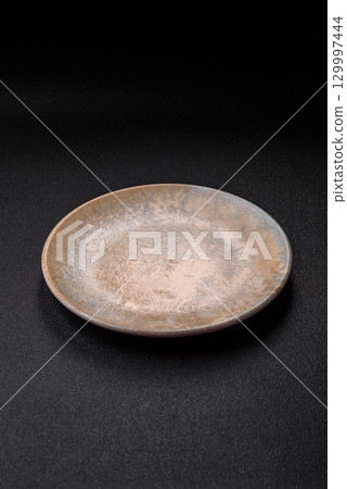 Empty round black plate for food, kitchen utensils on dining table. Empty plate 129997444