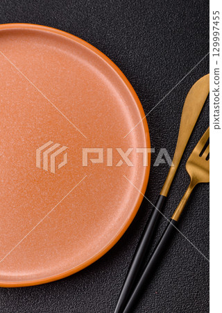 Empty round black plate for food, kitchen utensils on dining table. Empty plate 129997455