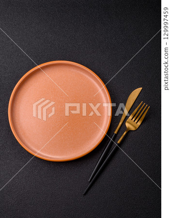 Empty round black plate for food, kitchen utensils on dining table. Empty plate 129997459