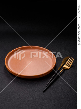Empty round black plate for food, kitchen utensils on dining table. Empty plate 129997460