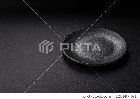 Empty round black plate for food, kitchen utensils on dining table. Empty plate 129997461