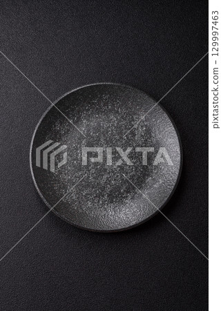 Empty round black plate for food, kitchen utensils on dining table. Empty plate Empty round black plate for food, kitchen utensils on dining table. Empty plate 129997463