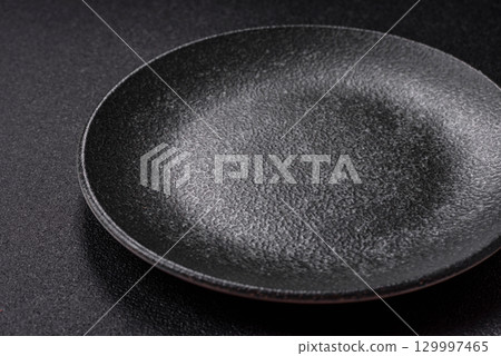 Empty round black plate for food, kitchen utensils on dining table. Empty plate Empty round black plate for food, kitchen utensils on dining table. Empty plate 129997465