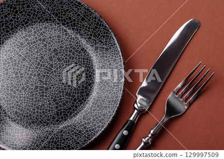 Empty round black plate for food, kitchen utensils on dining table. Empty plate Empty round black plate for food, kitchen utensils on dining table. Empty plate 129997509