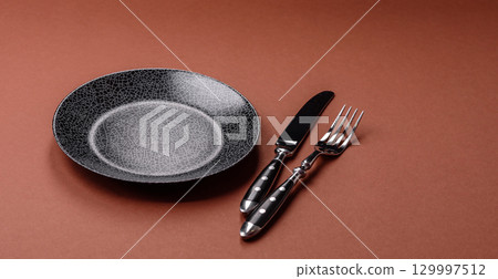 Empty round black plate for food, kitchen utensils on dining table. Empty plate 129997512
