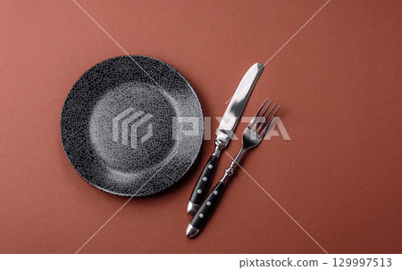Empty round black plate for food, kitchen utensils on dining table. Empty plate Empty round black plate for food, kitchen utensils on dining table. Empty plate 129997513