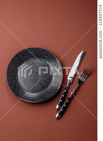 Empty round black plate for food, kitchen utensils on dining table. Empty plate Empty round black plate for food, kitchen utensils on dining table. Empty plate 129997514