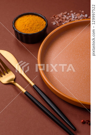 Empty round black plate for food, kitchen utensils on dining table. Empty plate 129997522