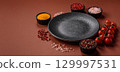 Empty round black plate for food, kitchen utensils on dining table. Empty plate 129997531