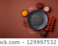 Empty round black plate for food, kitchen utensils on dining table. Empty plate 129997532